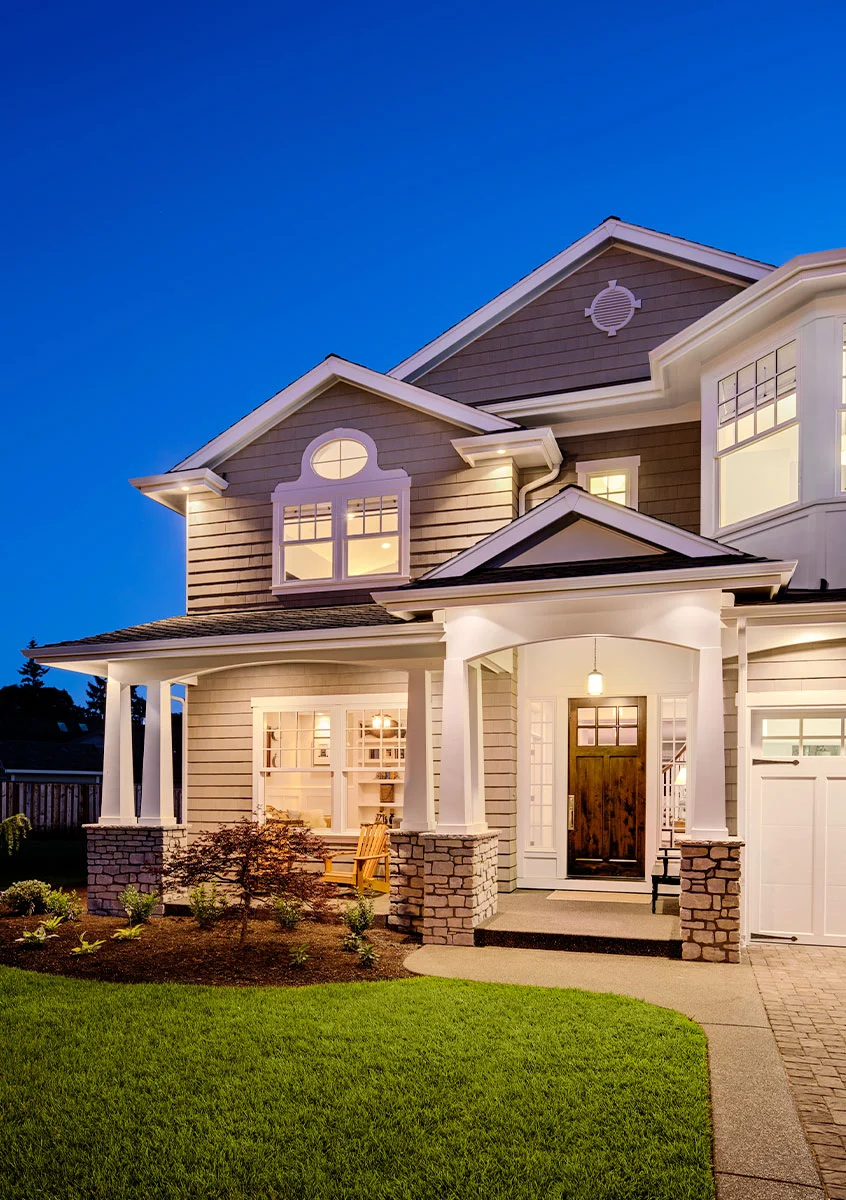 A warmly lit new home at dusk